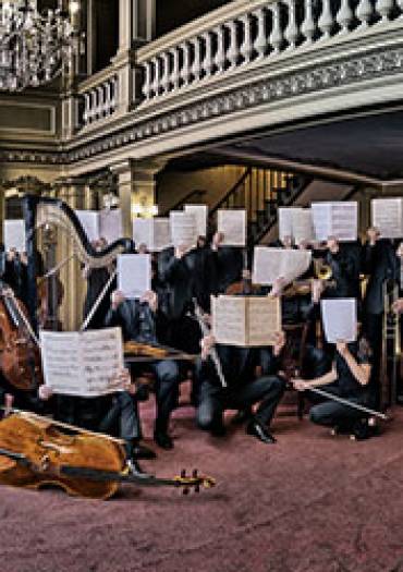 image du musiciens de l'orchetsre visages cachés par une partition ouverte
