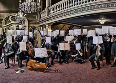 image du musiciens de l'orchetsre visages cachés par une partition ouverte